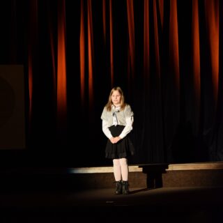 Na scenie dziewczynka recytująca wiersz podczas konkursu