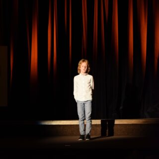 Na scenie chłopiec recytujący wiersz podczas konkursu